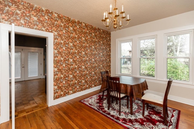 dining room with hardwood / wood-style flooring, a notable chandelier, a textured ceiling, and french doors