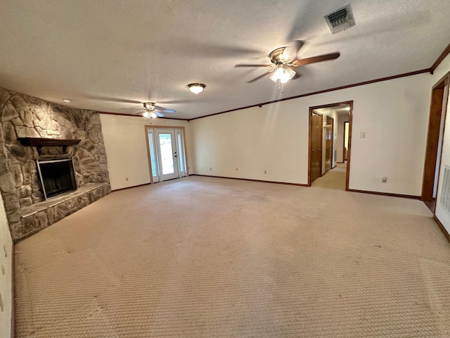 unfurnished living room featuring ceiling fan, a stone fireplace, light colored carpet, and a textured ceiling