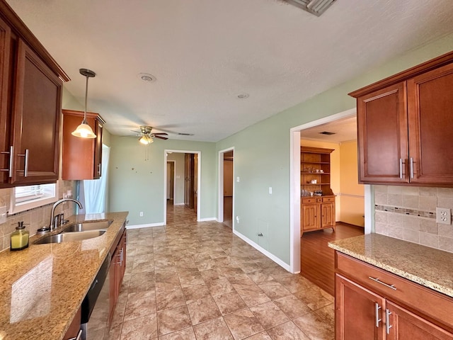 kitchen with light stone countertops, backsplash, ceiling fan, sink, and pendant lighting