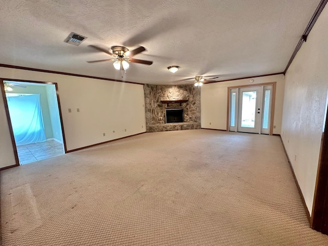 unfurnished living room featuring ceiling fan, a stone fireplace, light colored carpet, a textured ceiling, and ornamental molding