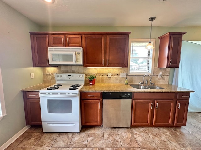 kitchen with pendant lighting, light stone countertops, white appliances, and sink