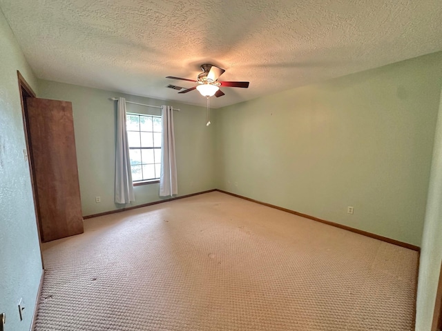 carpeted spare room with a textured ceiling and ceiling fan