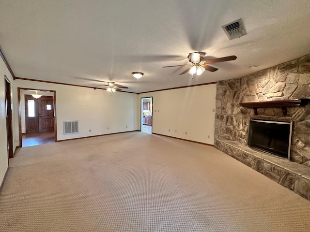 unfurnished living room featuring a textured ceiling, light colored carpet, ceiling fan, crown molding, and a fireplace