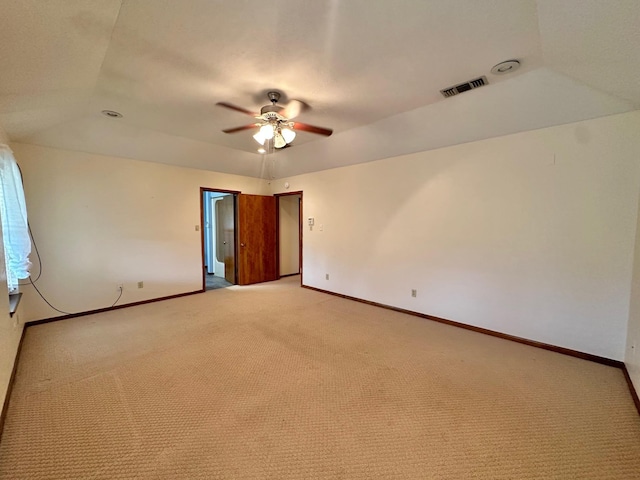 spare room with light carpet, a tray ceiling, and ceiling fan