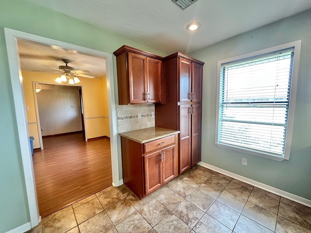 kitchen featuring decorative backsplash, ceiling fan, light tile patterned flooring, and a healthy amount of sunlight