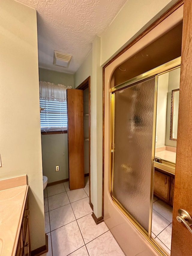 bathroom with an enclosed shower, a textured ceiling, vanity, tile patterned flooring, and toilet