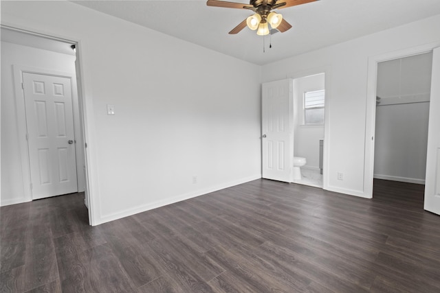 unfurnished bedroom with a spacious closet, connected bathroom, ceiling fan, a closet, and dark wood-type flooring