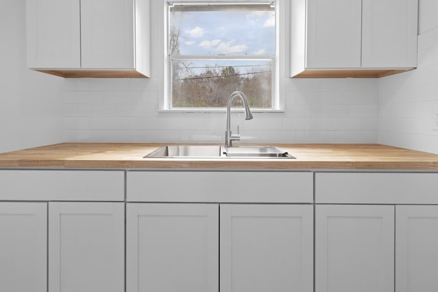 kitchen featuring sink, white cabinetry, and wood counters