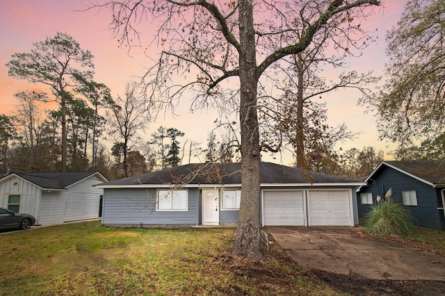 single story home featuring a garage and a yard