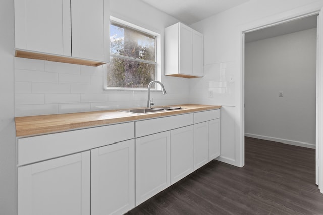 kitchen featuring white cabinets, butcher block counters, dark hardwood / wood-style floors, and sink