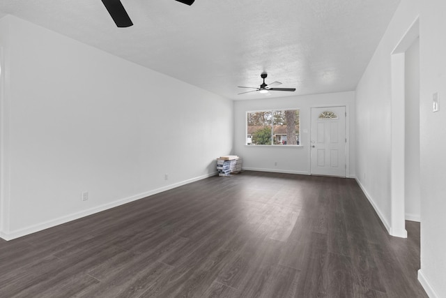 unfurnished living room featuring ceiling fan, dark wood-type flooring, and a textured ceiling