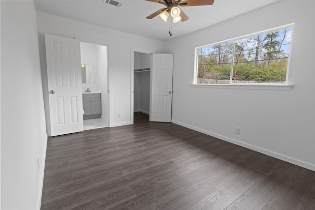 unfurnished bedroom with a closet, ceiling fan, dark hardwood / wood-style flooring, a spacious closet, and ensuite bathroom