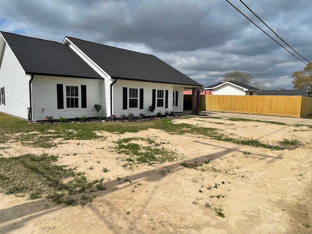 rear view of property featuring roof with shingles and fence