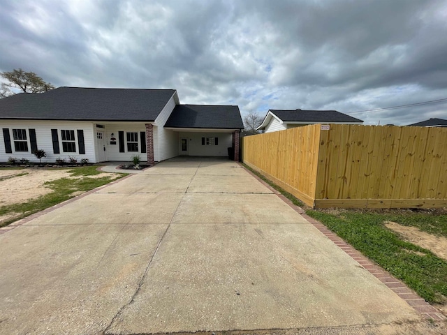 view of front of property with concrete driveway, fence, brick siding, and a carport