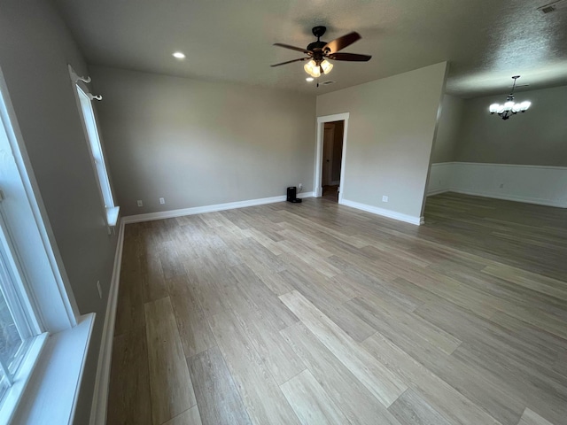 spare room featuring light wood finished floors, recessed lighting, ceiling fan with notable chandelier, and baseboards