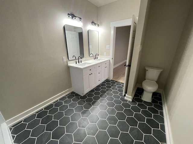 full bath with a sink, toilet, double vanity, and tile patterned floors