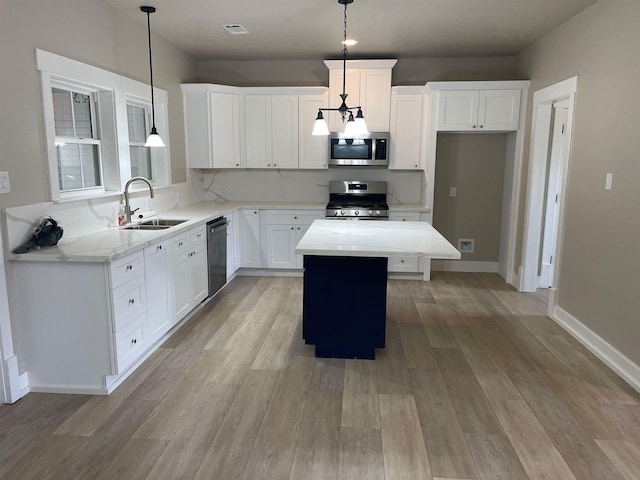 kitchen featuring appliances with stainless steel finishes, a kitchen island, light wood-style floors, and a sink