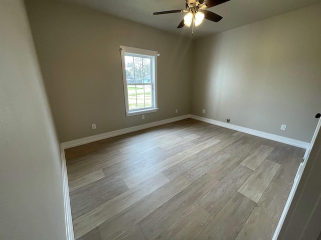 empty room with wood finished floors, baseboards, and ceiling fan