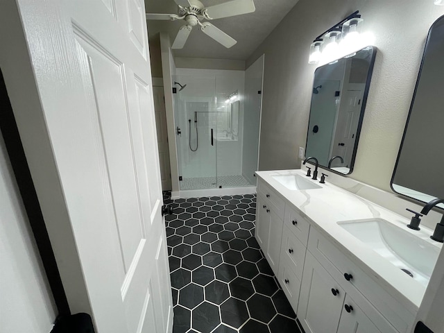 full bath with a ceiling fan, a shower stall, double vanity, and a sink