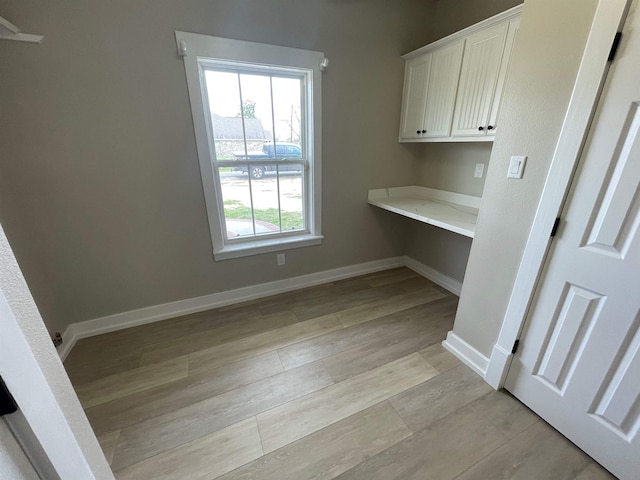 interior space with light wood-style floors, baseboards, and built in study area