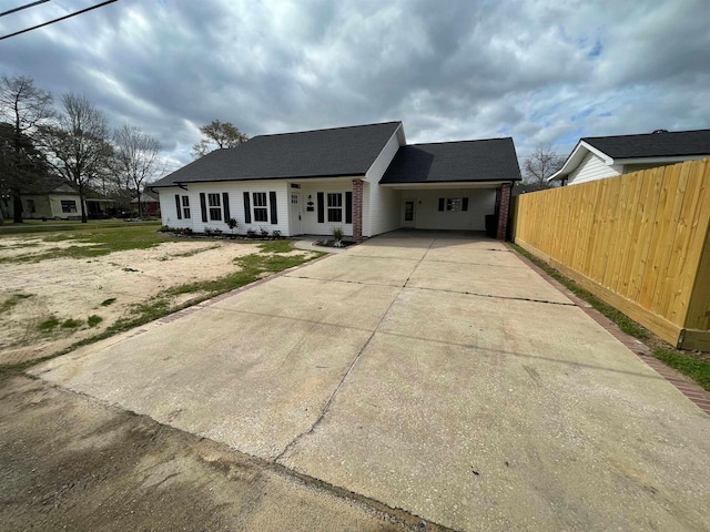 view of front facade featuring brick siding, concrete driveway, and fence