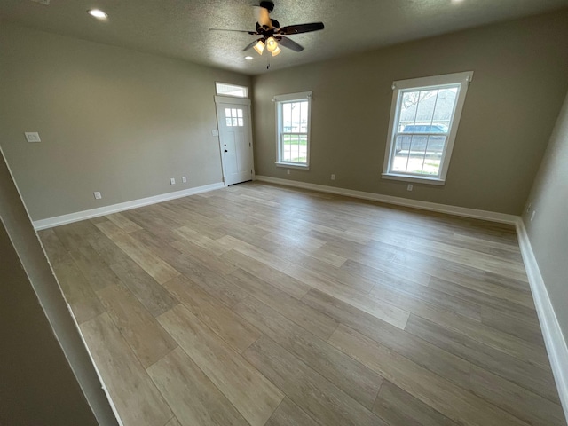 empty room with baseboards, light wood-type flooring, recessed lighting, a textured ceiling, and a ceiling fan