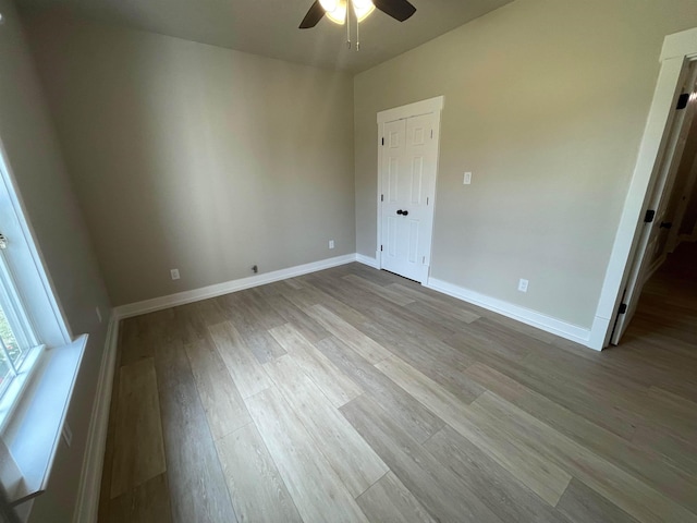 spare room with baseboards, wood finished floors, and a ceiling fan