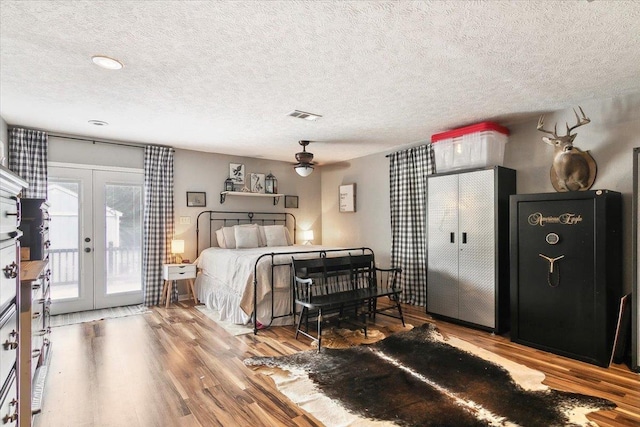 bedroom featuring hardwood / wood-style floors, a textured ceiling, access to outside, and french doors