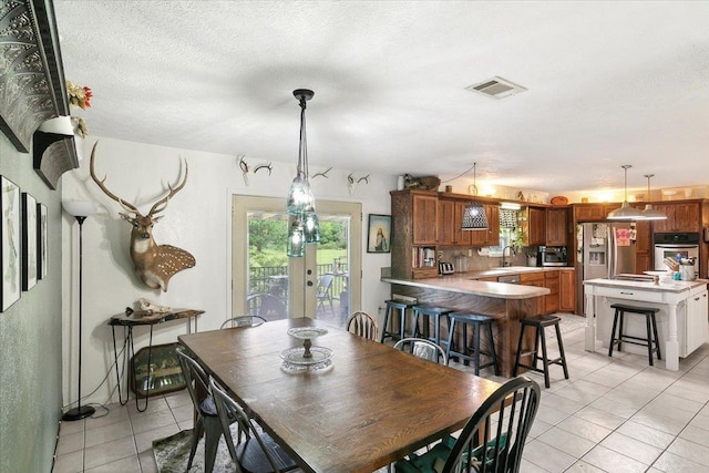 tiled dining space featuring a textured ceiling, sink, and french doors