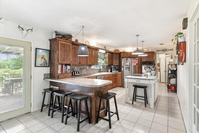 kitchen with kitchen peninsula, a kitchen breakfast bar, stainless steel appliances, sink, and pendant lighting