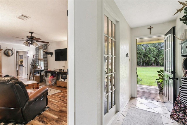 entryway with french doors, a textured ceiling, light tile patterned floors, and ceiling fan