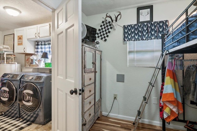 laundry room with washer and dryer, a textured ceiling, and light wood-type flooring