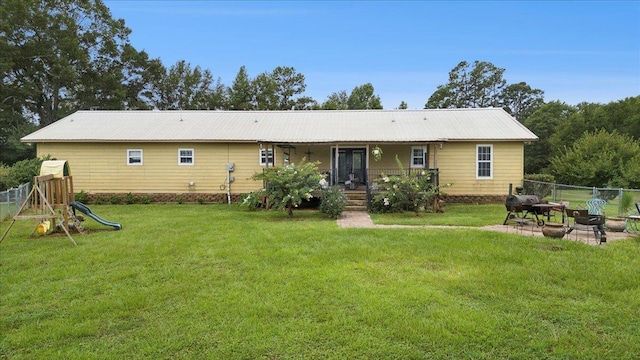 back of property featuring a yard and a playground