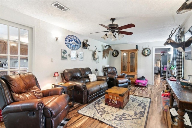 living room with wood-type flooring, a textured ceiling, and ceiling fan