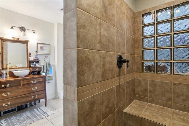 bathroom with tile patterned flooring, vanity, and a tile shower