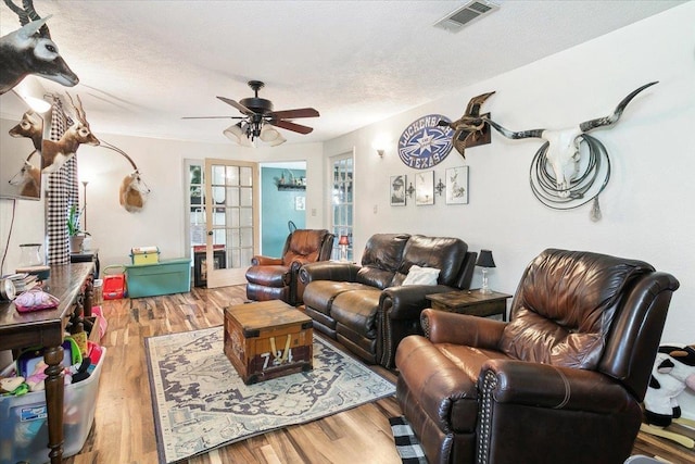 living room with ceiling fan, hardwood / wood-style floors, and a textured ceiling