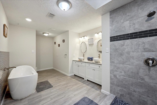 11503 Davidson Rd, Beaumont, TX 77705 - full bathroom with double vanity, wood finished floors, a soaking tub, a textured ceiling, and a tile shower