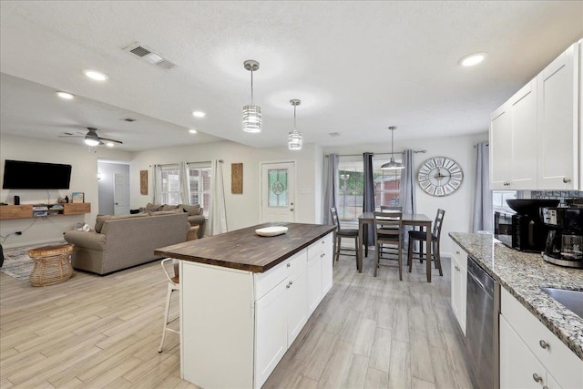 11503 Davidson Rd, Beaumont, TX 77705 - kitchen with stainless steel dishwasher, light wood finished floors, butcher block countertops, a breakfast bar area, and recessed lighting