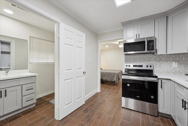 11503 Davidson Rd, Beaumont, TX 77705 - kitchen with stainless steel appliances, gray cabinets, ornamental molding, light countertops, and dark wood-style floors