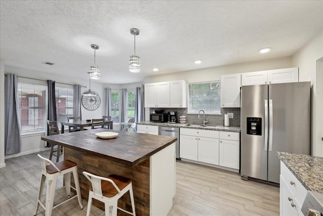 11503 Davidson Rd, Beaumont, TX 77705 - kitchen featuring stainless steel appliances, light stone countertops, light wood-style flooring, white cabinets, and tasteful backsplash