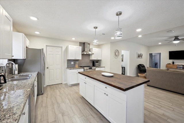 11503 Davidson Rd, Beaumont, TX 77705 - kitchen featuring wall chimney range hood, open floor plan, butcher block countertops, light wood-style floors, and decorative backsplash