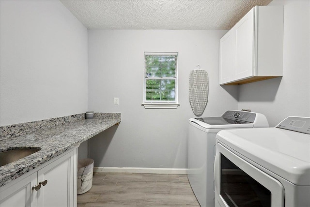 11503 Davidson Rd, Beaumont, TX 77705 - washroom with washer and dryer, cabinet space, light wood finished floors, and a textured ceiling