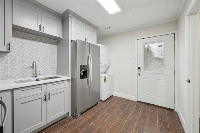 11503 Davidson Rd, Beaumont, TX 77705 - kitchen featuring stainless steel refrigerator with ice dispenser, stacked washer / drying machine, decorative backsplash, light countertops, and dark wood-style flooring