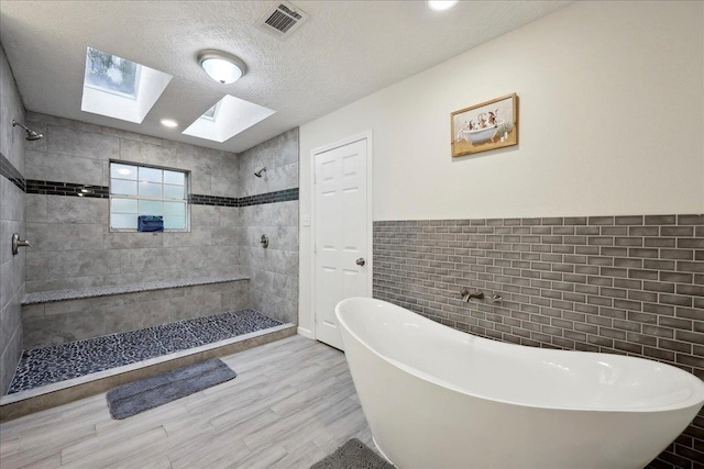 11503 Davidson Rd, Beaumont, TX 77705 - full bath featuring a skylight, tile walls, a freestanding bath, tiled shower, and wood finished floors