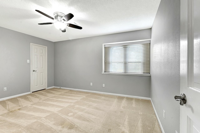 empty room featuring light carpet, a textured ceiling, and ceiling fan