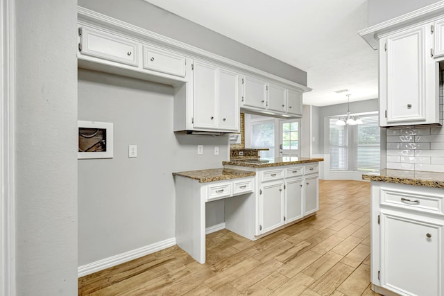 kitchen with white cabinets, decorative backsplash, light hardwood / wood-style floors, and dark stone counters