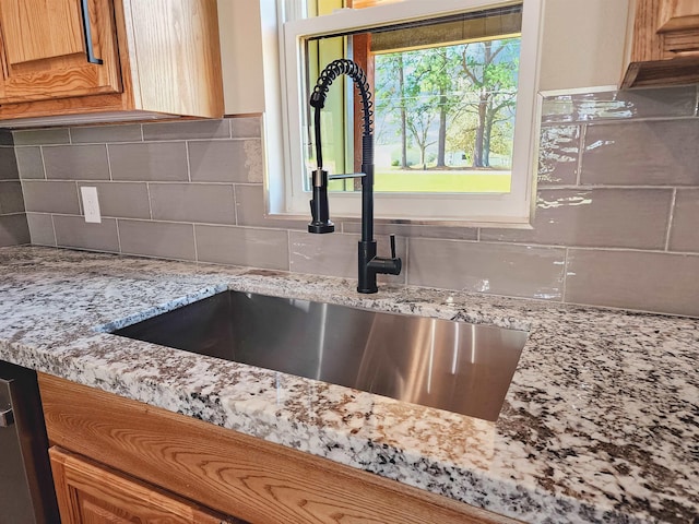 interior details featuring a sink, tasteful backsplash, dishwasher, and light stone countertops