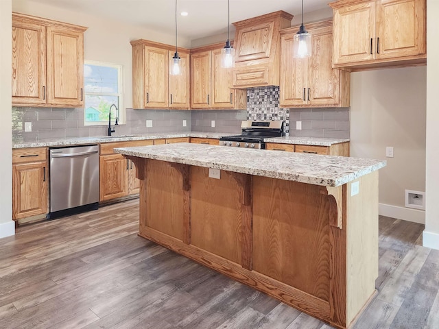 kitchen featuring a breakfast bar, baseboards, a kitchen island, stainless steel appliances, and wood finished floors