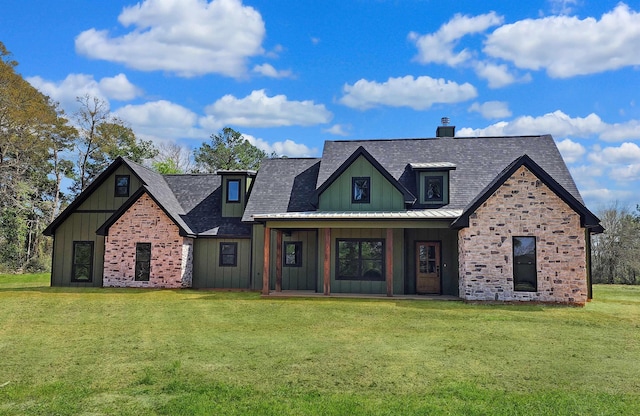 modern farmhouse featuring board and batten siding, metal roof, a front yard, and a chimney