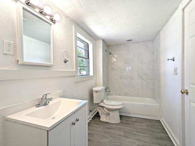 full bathroom featuring vanity, tiled shower / bath combo, toilet, and a textured ceiling